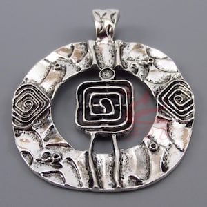 May include: Silver pendant with a circular design featuring a square with a spiral pattern in the center. The pendant has a textured surface and a loop at the top for attaching a chain.