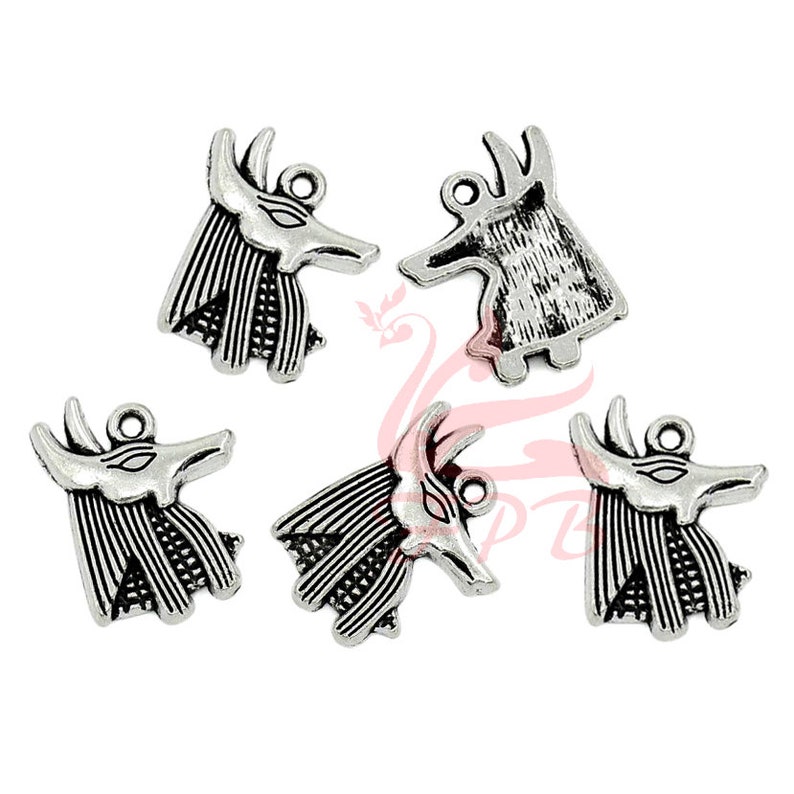 May include: Five silver-toned metal charms in the shape of an Anubis head. The charms have a detailed design and are perfect for jewelry making or crafting.