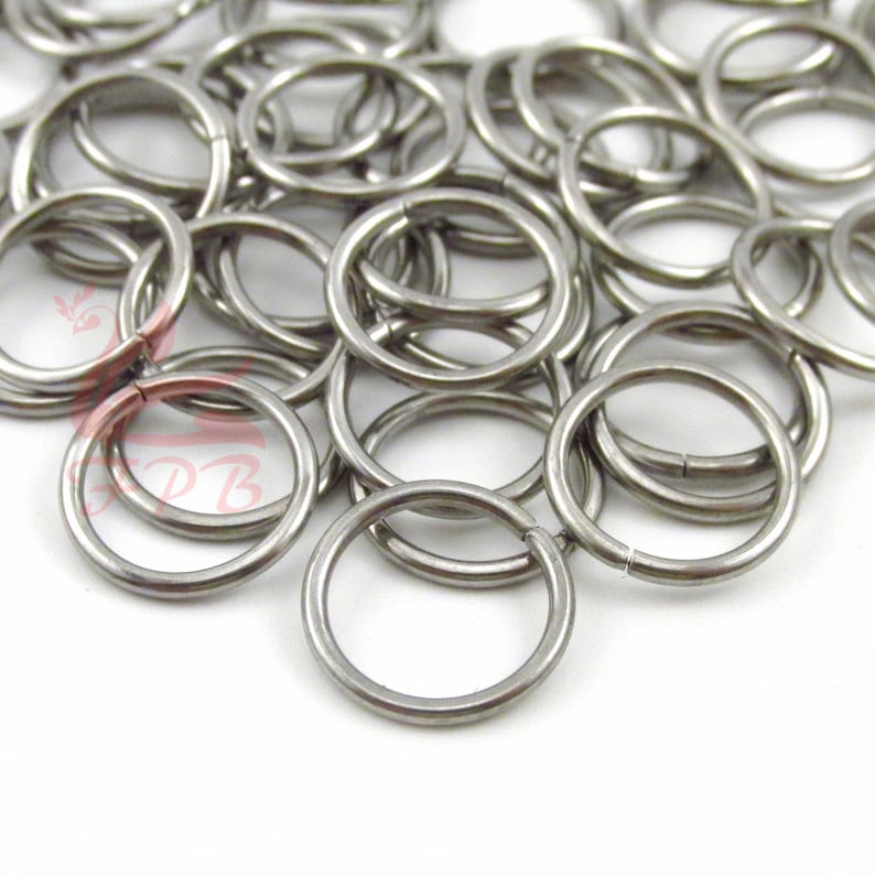 May include: A pile of silver jump rings, a type of metal ring used for jewelry making and crafting.