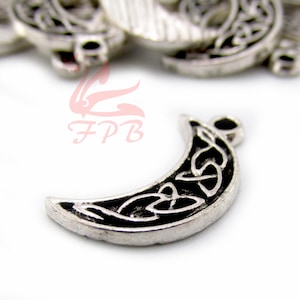 May include: Silver-toned crescent moon charm with a black Celtic knot design. The charm has a loop at the top for attaching to jewelry. The moon shape is detailed and has a vintage appearance.