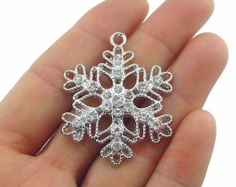May include: Silver snowflake charm with clear rhinestones. The snowflake is detailed with a scalloped edge and has a loop at the top for hanging.