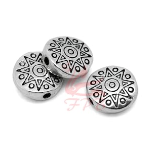 May include: Three silver-toned round beads with a black starburst design. Each bead has a hole for stringing.