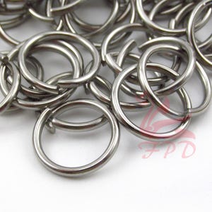 May include: A pile of silver-colored metal key rings. The key rings are all the same size and shape, and they are arranged in a random pattern.