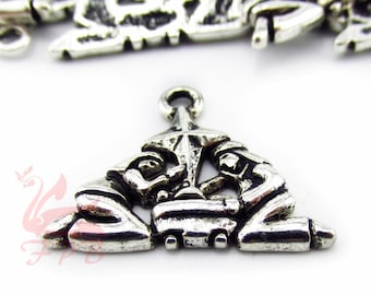 May include: Silver charm pendant featuring a triangular design with three figures kneeling around a central figure. The figures are intricately detailed and have a vintage look.