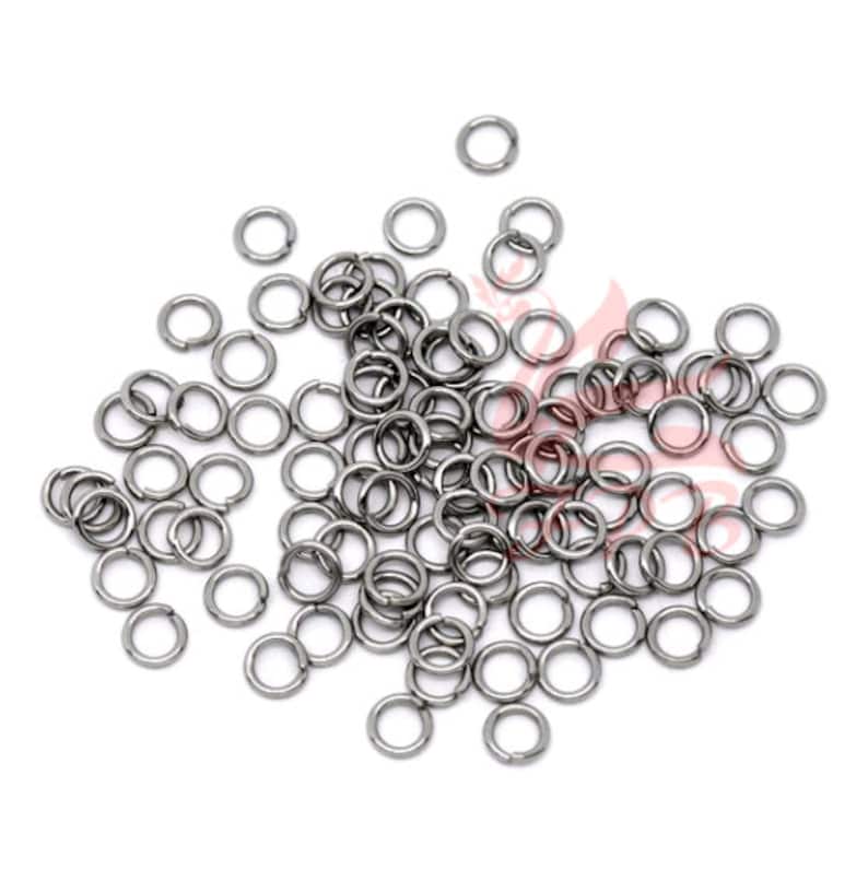May include: A large pile of silver jump rings. The rings are small and round, and they are all the same size.