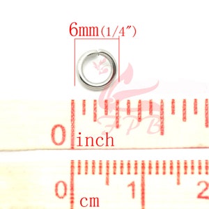 May include: A silver jump ring measuring 6mm (1/4 inch) in diameter. The ring is shown next to a ruler with inch and centimetre markings.