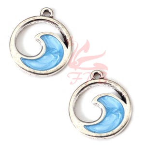 Op de afbeelding: Twee zilverkleurige golfbedels met een lichtblauwe emaille vulling. Elke bedel heeft een cirkelvormig frame met een golfontwerp. De bedels hebben een kleine lus aan de bovenkant om te bevestigen. Ideaal voor sieraden met oceaanthema.