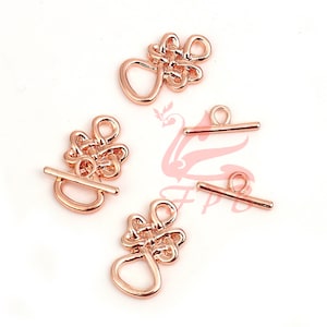 May include: Four rose gold toggle clasps, two with a knot design and two with a simple bar design. These clasps are perfect for jewelry making or adding a touch of elegance to your projects.