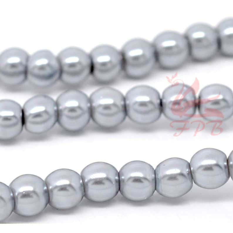 May include: A strand of silver-colored round pearl beads. The beads are smooth and shiny, and they are strung together on a clear thread.