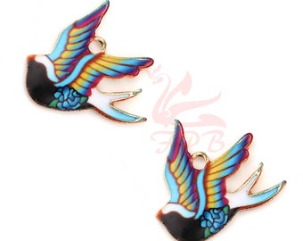 May include: Two gold-toned metal charms shaped like flying swallows. The swallows are painted with a colorful design of blue, yellow, red, and white. Each swallow has a small loop at the top for attaching to a necklace or bracelet.