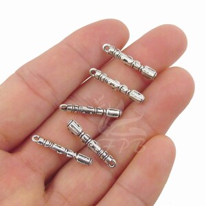 K&ouml;nnte beinhalten: F&uuml;nf silberfarbene Metall-Anh&auml;nger in Form eines kleinen, detaillierten, verzierten, zylindrischen Zauberstabs oder Zepters. Die Anh&auml;nger haben oben eine &Ouml;se zum Anbringen an Schmuck oder anderen Bastelarbeiten.