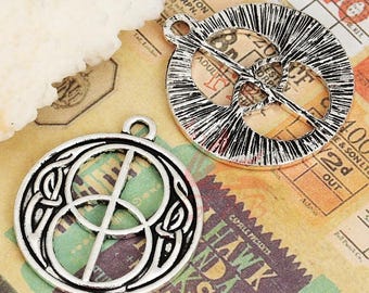Puede incluir: Dos abalorios de metal plateados con diseños de nudos celtas. Un abalorio presenta un diseño circular con una cruz en el interior, el otro abalorio presenta un diseño circular con dos círculos superpuestos.