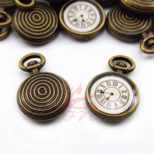 May include: Antique gold-tone pocket watch charms with a Roman numeral clock face and a spiral design.