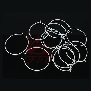May include: A group of silver hoop earrings, all of the same size and shape, are piled together on a black surface.