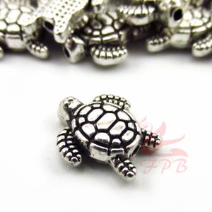 May include: Silver turtle charm with a detailed shell design. The charm is small and perfect for jewellery making or crafting.