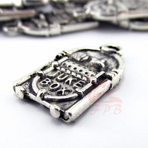 May include: Silver charm in the shape of a vintage jukebox with the words "Jukebox" and "Box" embossed on the front.