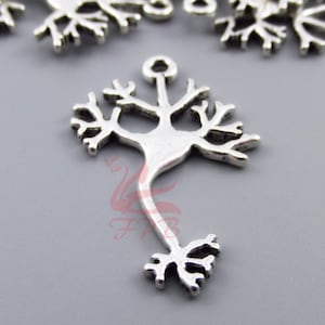 May include: Silver charm in the shape of a tree with a loop at the top for attaching to a necklace or bracelet.