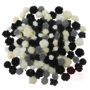 May include: A selection of artificial flowers in various sizes and styles. The flowers are in shades of black, white, and grey, including roses and other floral designs. These decorative flowers are suitable for crafts and embellishments.