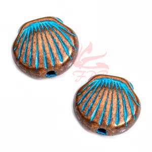 Puede incluir: Dos cuentas de concha de color cobre con un diseño de esmalte azul turquesa. Las cuentas tienen un agujero en el centro para enhebrar.