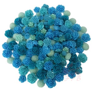 Pode incluir: Uma coleção de pequenas flores de plástico em vários tons de azul e verde-azulado. A variedade inclui rosas, outras formas florais e botões esféricos. As flores estão agrupadas, criando um arranjo visualmente atraente.