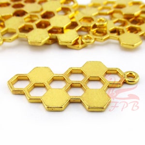 Puede incluir: Encanto de metal dorado en forma de panal de abeja con un bucle para sujetarlo a joyas o manualidades. El encanto está hecho de un metal delgado y tiene un diseño delicado.