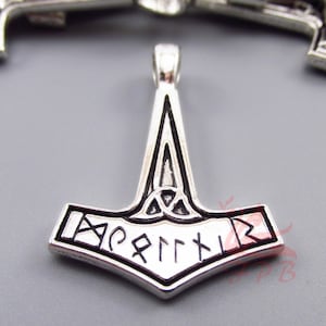 May include: Silver pendant in the shape of a hammer with a Celtic knot design and runes inscribed around the hammer head.