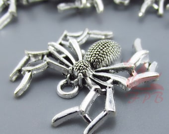 May include: Silver-toned spider charm with a web design. The spider has a textured body and eight legs. The charm has a loop at the top for attaching to jewellery.