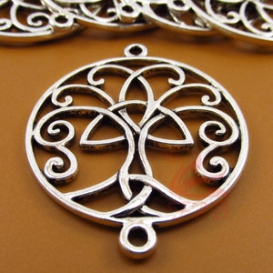 May include: Silver-toned metal charm featuring a Celtic tree of life design. The charm is circular with intricate, swirling patterns and a tree-like central motif. It has a loop at the top and bottom for attachment, suitable for jewelry making or crafts.