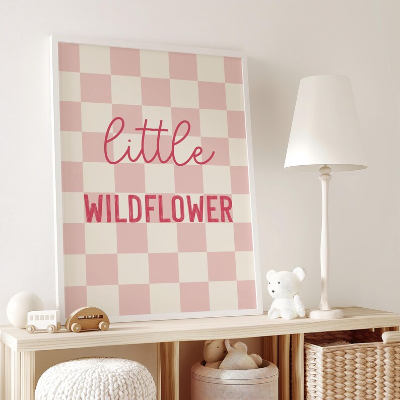 May include: A pink and white checkered print with the text "little wildflower" in pink lettering.
