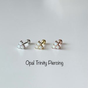 Puede incluir: Tres pendientes de piercing de trinidad de ópalo en plata, oro y oro rosa. Cada pendiente tiene tres piedras de ópalo en forma de triángulo.