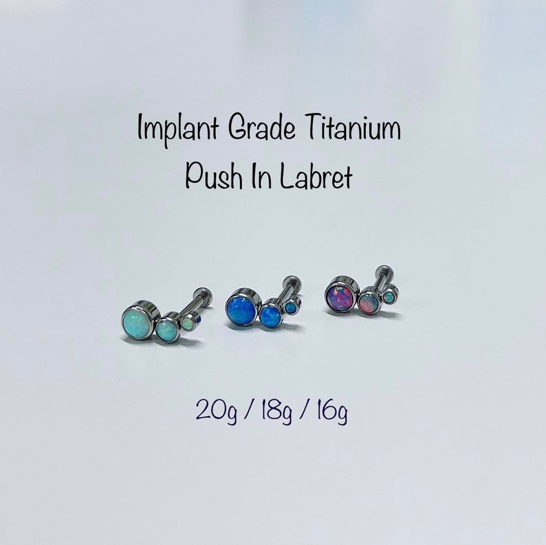 May include: Three titanium labrets with opal stones. The labrets are available in 20g, 18g, and 16g. The opal stones are blue, light blue, and pink.