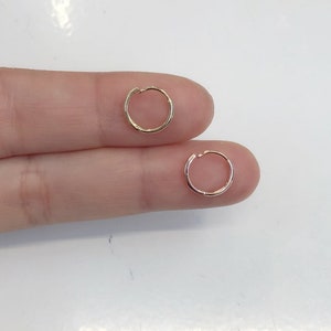 May include: Two gold hoop earrings, one is a slightly larger diameter than the other.