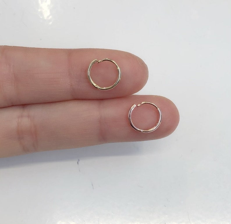 May include: Two gold hoop earrings, one is a slightly larger diameter than the other.
