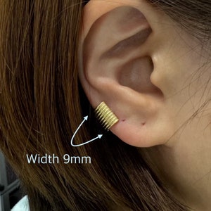 May include: Gold ear cuff with a textured, ribbed design. The cuff is 9mm wide.
