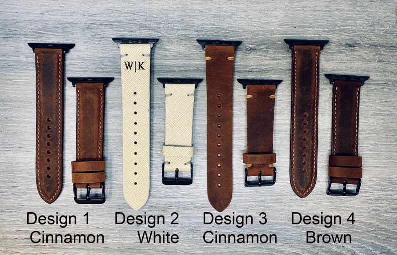 May include: An assortment of leather watch bands in various shades of brown and white. The bands feature black hardware and are labeled with the words "Design 1 Cinnamon", "Design 2 White", "Design 3 Cinnamon", and "Design 4 Brown". One band is engraved with the initials "W|K".