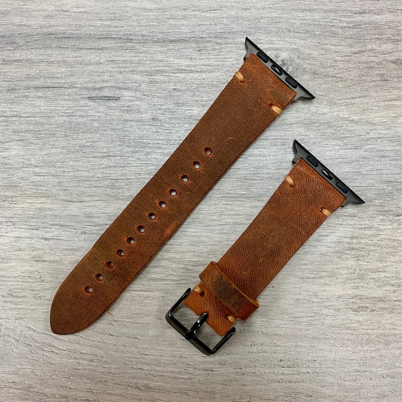 Peut inclure: Deux bracelets de montre en cuir marron avec des fermoirs m&eacute;talliques noirs et des coutures. Les bracelets sont con&ccedil;us pour les montres Apple.