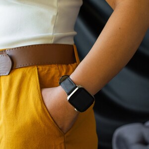 K&ouml;nnte beinhalten: Eine Person tr&auml;gt ein wei&szlig;es Tanktop und eine senfgelbe Hose mit einem braunen Lederg&uuml;rtel. Die Person tr&auml;gt eine schwarze Smartwatch mit einem silbernen Armband am linken Handgelenk.