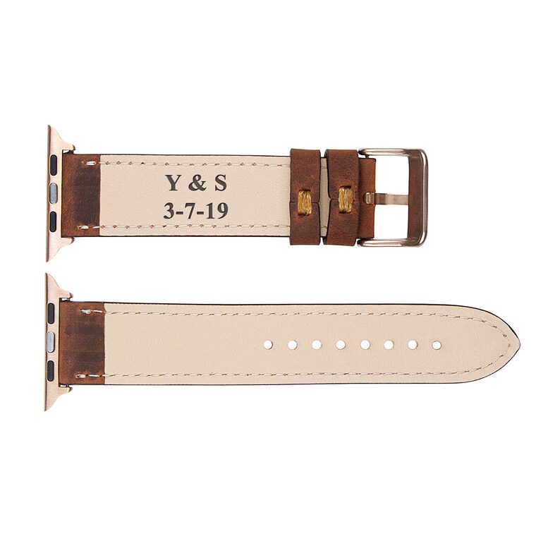 May include: Brown leather Apple Watch band with a rose gold buckle. The band is engraved with "Y & S 3-7-19".