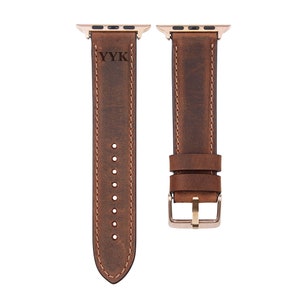 May include: A brown leather watch band with a gold buckle and a YYK logo. The band is designed for an Apple Watch.