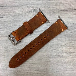 Peut inclure: Deux bracelets de montre en cuir marron avec des fermoirs en m&eacute;tal argent&eacute;. Les bracelets sont con&ccedil;us pour les montres Apple.