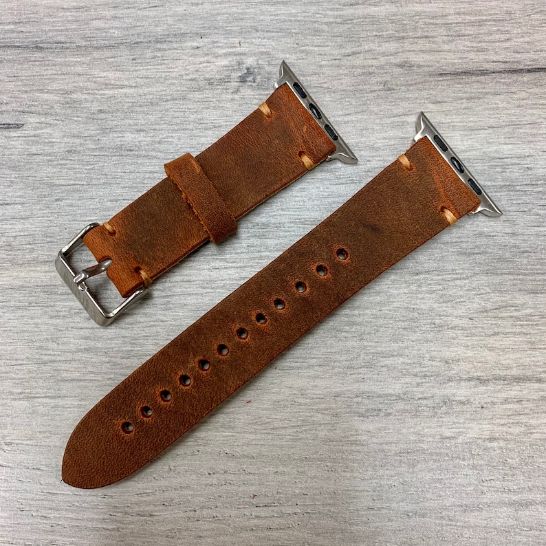 Peut inclure: Deux bracelets de montre en cuir marron avec des fermoirs en m&eacute;tal argent&eacute;. Les bracelets sont con&ccedil;us pour les montres Apple.