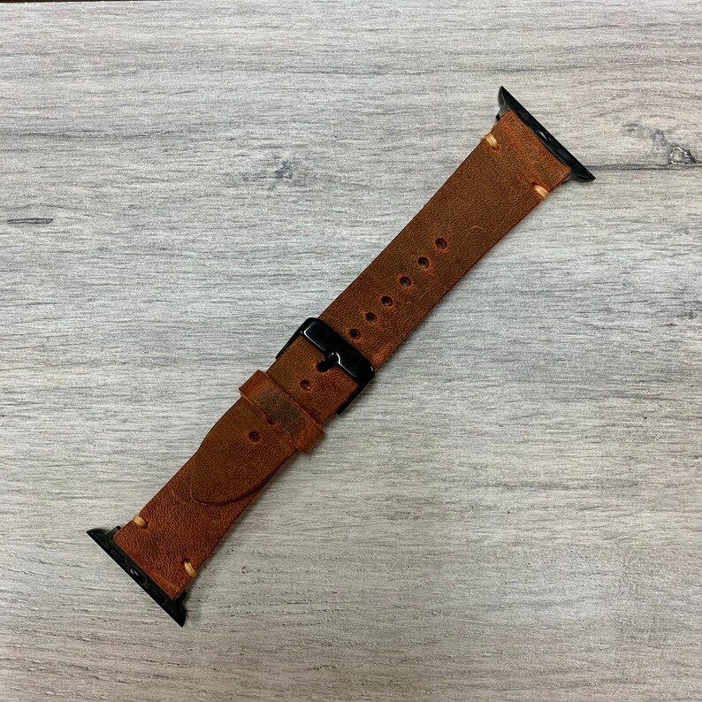 Peut inclure: Un bracelet de montre en cuir marron avec des accessoires en m&eacute;tal noir. Le bracelet a un aspect vieilli et est con&ccedil;u pour une montre connect&eacute;e.