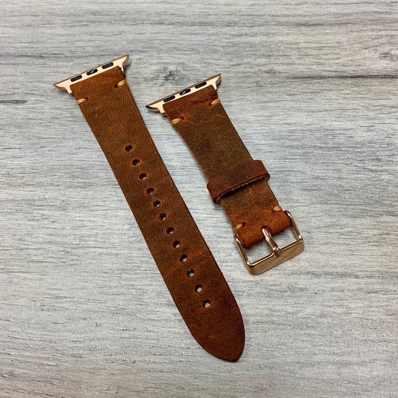 Peut inclure: Deux bracelets de montre en cuir marron avec des accessoires dor&eacute;s. Les bracelets sont con&ccedil;us pour les montres Apple.