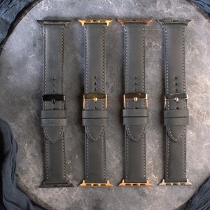 K&ouml;nnte beinhalten: Vier schwarze Lederarmb&auml;nder mit verschiedenen farbigen Verschl&uuml;ssen. Die Armb&auml;nder sind alle im gleichen Stil und haben wei&szlig;e N&auml;hte. Die Verschl&uuml;sse sind schwarz, gold, ros&eacute;gold und silber.