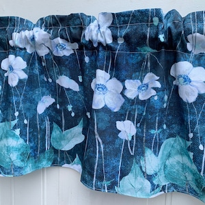 May include: A blue and white floral valance with a watercolor-like design. The valance features white flowers with blue centers and green leaves on a dark blue background.