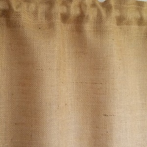 K&ouml;nnte beinhalten: Eine braune Jute-Gardine mit gerafftem Oberteil und geradem Unterteil.
