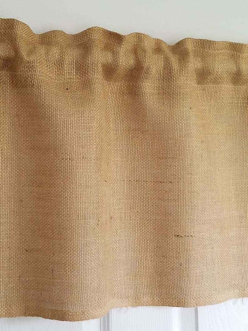 K&ouml;nnte beinhalten: Eine braune Jute-Gardine mit gerafftem Oberteil und geradem Unterteil.
