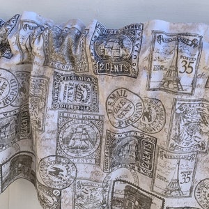 May include: A beige fabric with a vintage postage stamp pattern. The stamps feature images of ships, the Eiffel Tower, and other designs. The text on the stamps includes "Postage & Revenue", "One Cent Prepaid", "2 Cents", "Postes 35", and "La Guaira".