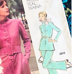 May include: A Vogue Americana Teal Traina sewing pattern envelope for a jacket and pants set, featuring a photograph of a pink coat and an illustration of a teal suit. The text reads Vogue Americana, Teal Traina, 2812, and BUST 32.5 INCHES.