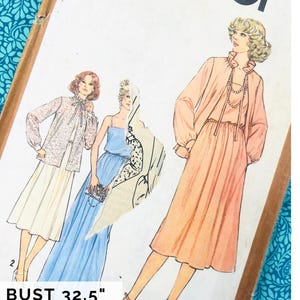 以下が含まれることがあります： Simplicity 8701のヴィンテージ型紙封筒。長袖ブラウスとスカート、ノースリーブのマキシ丈ドレス、フリル襟のドレスという3種類の衣装のイラストが描かれています。テキストには「BUST 83 cm COMPLETE 1970S」と記載されています。
